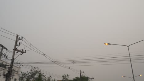 Ciudad-Gris-Con-Smog-Y-Humo-Sobre-árboles-Y-Líneas-Eléctricas-Con-Un-Avión-Volando-En-Chiang-Mai,-Tailandia