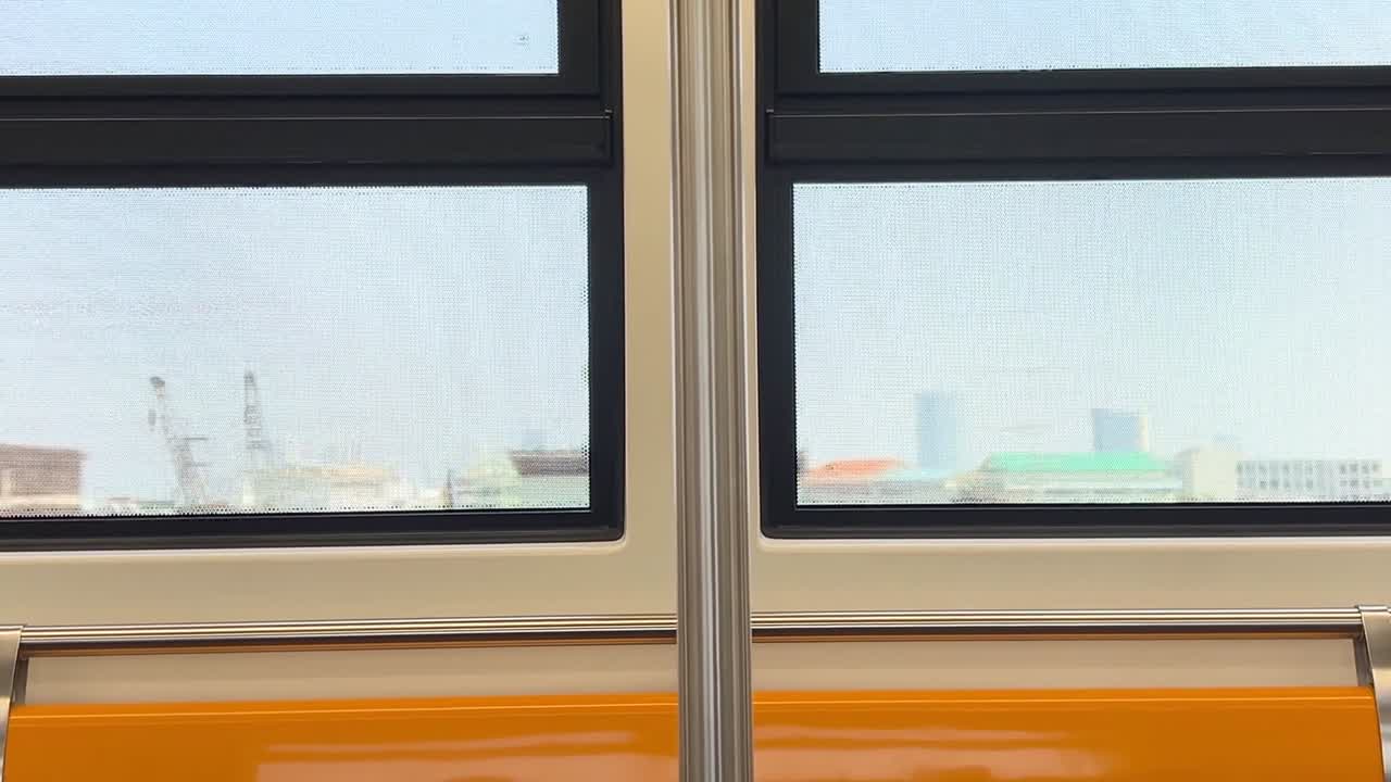 Static close-up shot of empty orange train seats with passing urban skyline through windows