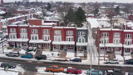 aerial of colorful row houses covered in snow, decorated for holidays