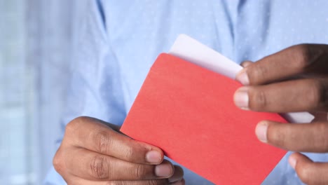 persona sosteniendo un sobre rojo con una carta dentro