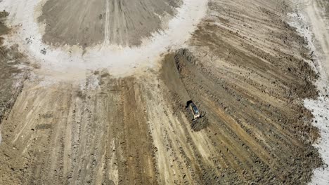 Aerial-view,-the-skidster-pushes-the-soil-from-the-top-of-the-mountain-to-the-bottom