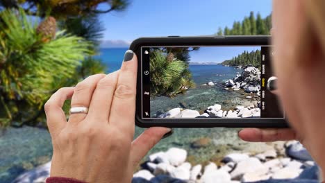 cinemagrafo en bucle de 4k de una mujer filmando el paisaje de la orilla del lago en un teléfono inteligente