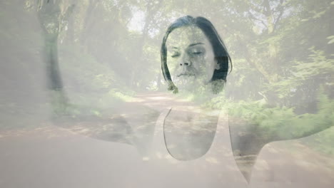 composición digital de mujer caucásica meditando contra la vista del camino del bosque