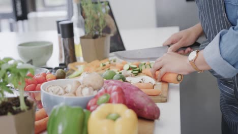 Midsection-of-biracial-woman-preparing-meal,-chopping-vegetables-in-kitchen,-slow-motion