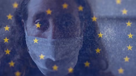 Digitales-Zusammengesetztes-Video-Der-EU-Flagge,-Die-Sich-Vor-Einer-Frau-Mit-Gesichtsmaske-Im-Hintergrund-Bewegt
