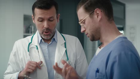 two serious caucasian male doctors discussing over documents in medical clinic