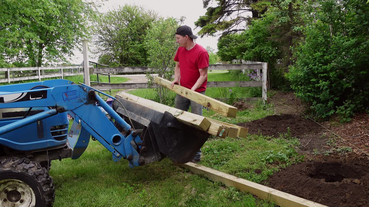 트랙터에서 울타리를 위해 나무 기둥을 꺼내는 남자, 정적 보기