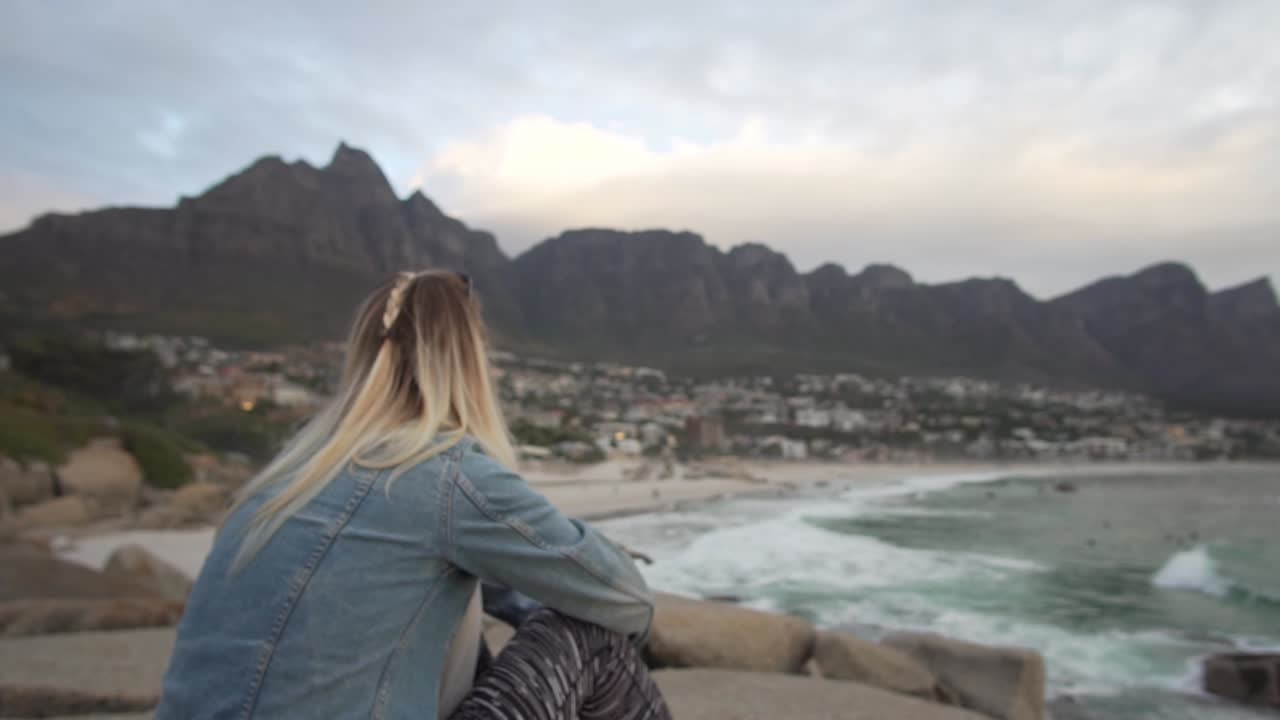 Young Woman looking at Table Mountain and the coast of Cape Town at Sunset in Camps Bay, South Africa in Slow Motion