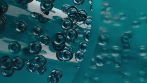 abstract microscopic flow of teal bubbles in a transparent tube