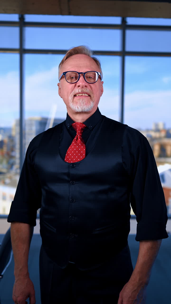 Smiling mature male in black shirt, vest and tie becomes serious quickly. Man approaches to camera looking suspiciously. Close up. Vertical video.