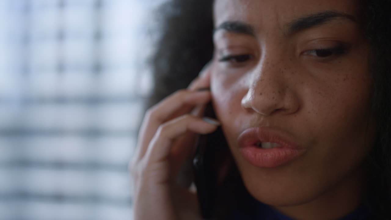 Anxious businesswoman manager talking mobile phone discussing finance in office.