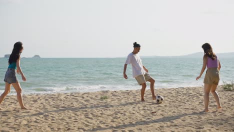 friends playing soccer on the beach