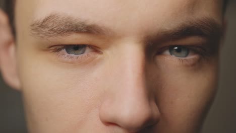 un joven caucásico con ojos grises frente a la cámara, un primer plano extremo