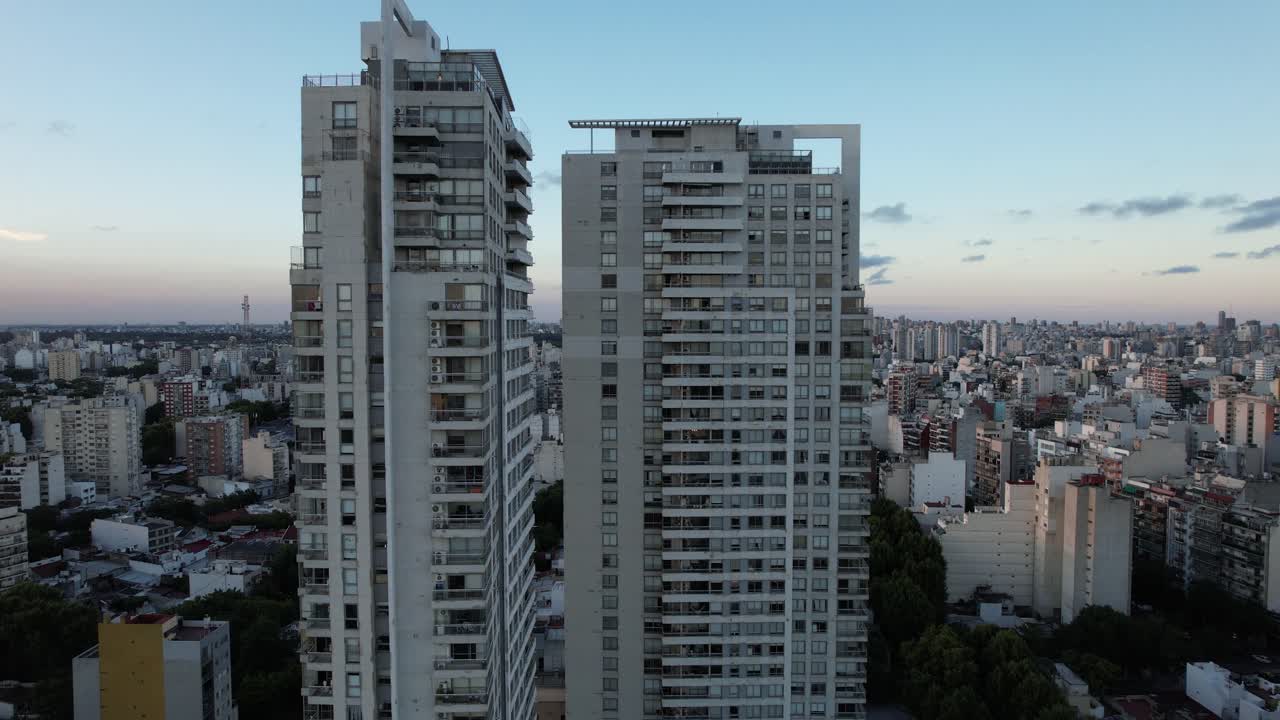 drone rising near large building in buenos aires with movement to the left showing the sunset