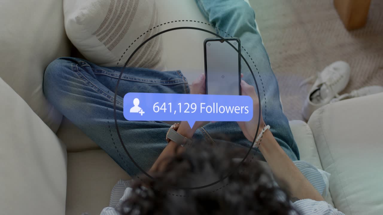 Man on couch holding phone, loading starting count bubble over screen, rising fast for social media