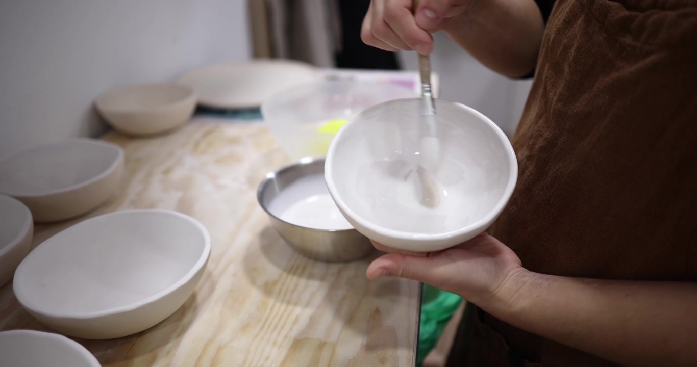Vasaio che smalta una ciotola di ceramica in studio