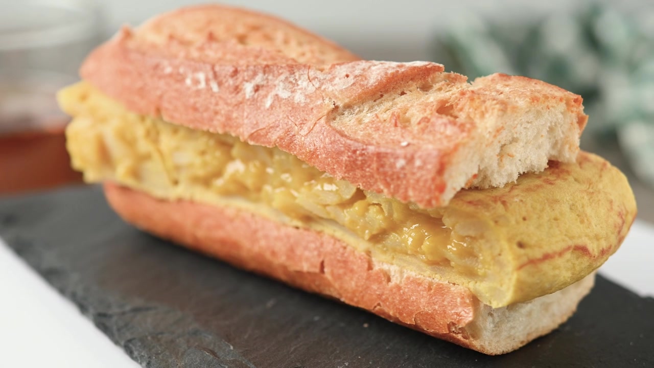 Panino con tortilla di patate spagnola su tavolo di legno. Bocadillo de tortilla