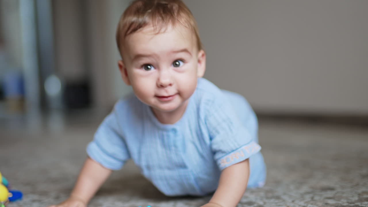 Adorable cheerful laughing toddler standing on all fours on the floor and swaying. Little kid playing with a toy.