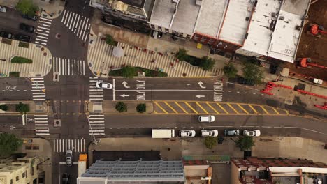 aerial top down shot over a quiet street as the drone camera descends with a few cars driving by