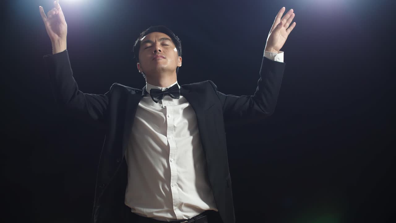 흑인 스튜디오에서 눈을 감고 몸짓을 하는 아시아인 지휘자