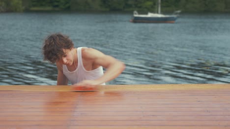 a young man manually sands roof planking of old wooden boat cabin roof