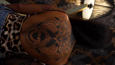 rear shot of young female woman with large flowery tattoo on back. slowmo, 4k