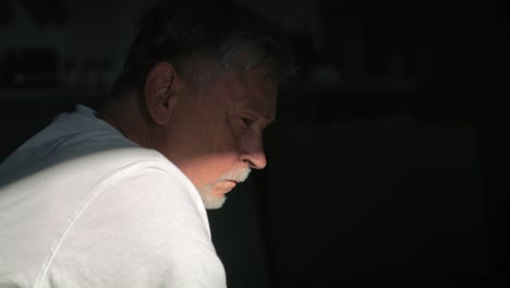 senior caucasian man with mental problem sitting in darkness.