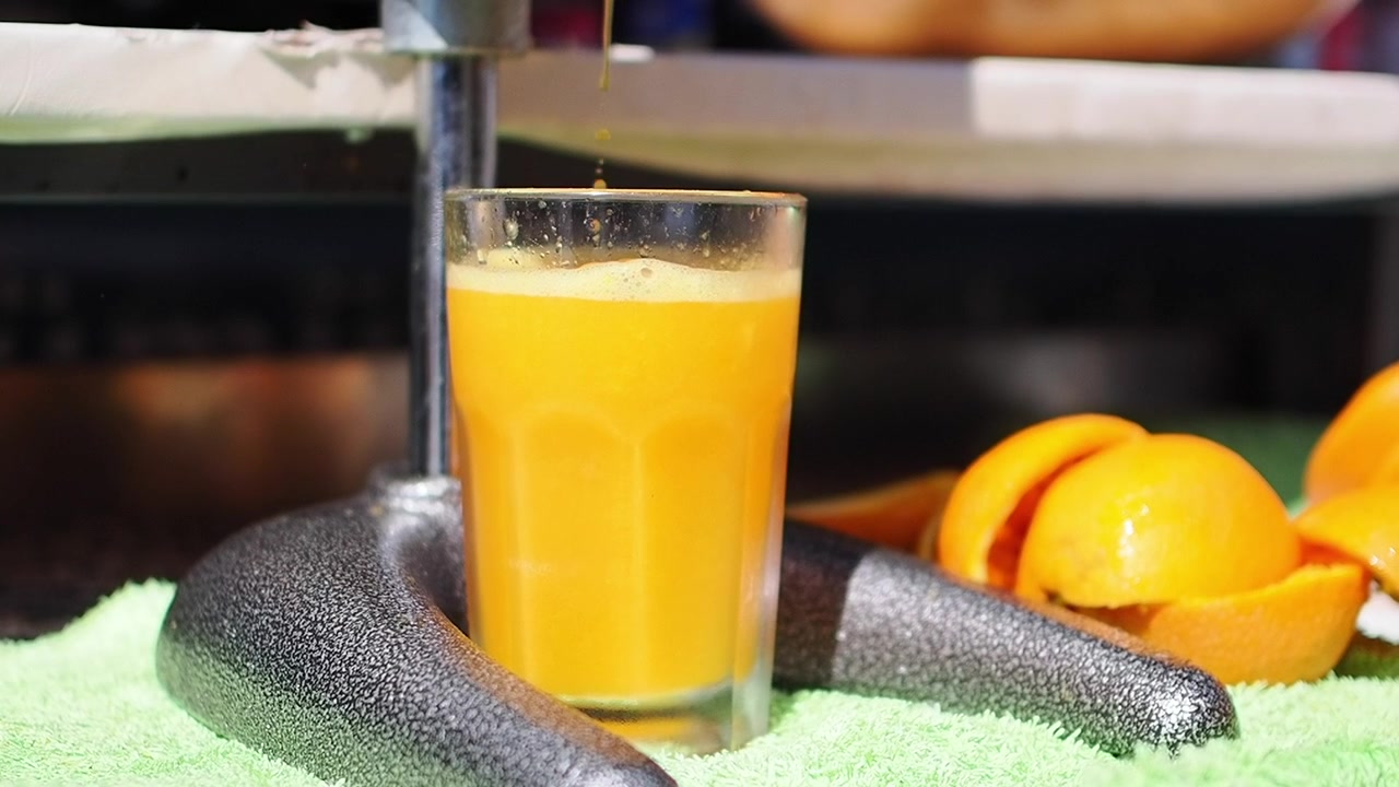 Frischer Orangensaft wird in ein Glas gegossen