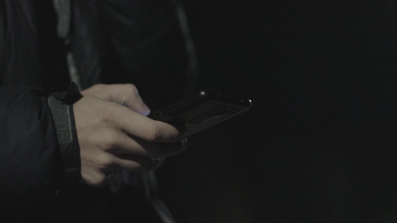 남자가 밤에 거리에서 드폰을 스크롤합니다.