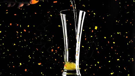 confetti falling over beer pouring into a glass against black background