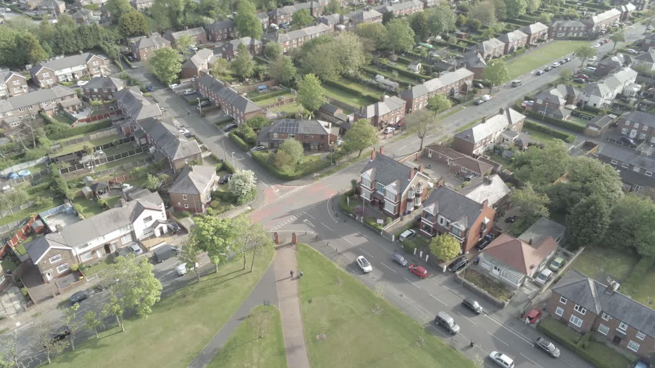 Drone aerial view overlooking British town houses gardens suburban residential overhead scene birds eye pan left