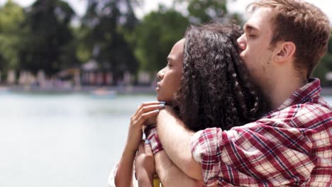 diverse couple hugging near lake