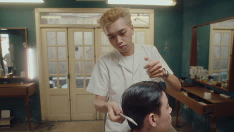 asian barber combing and spraying hair of client