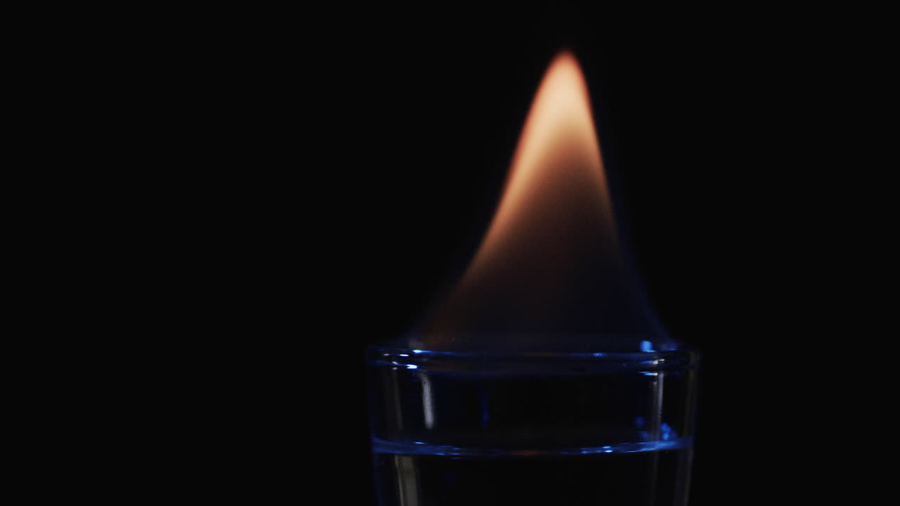 video de alcohol encendido en vidrio con llama de fuego naranja y copia de espacio en fondo negro