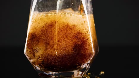 A detailed view of soda being poured into a glass filled with ice, showcasing bubbles and fizz.