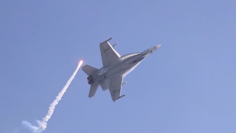 f/a-18 hornet performs an afterburner climb, releasing flares against a clear blue sky at avalon airshow, geelong