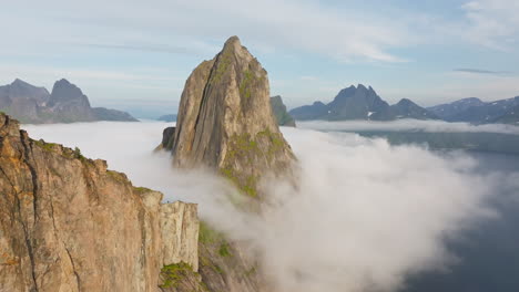 drone reveal sharp pointed arctic segla mountain surrounded by fog in norway