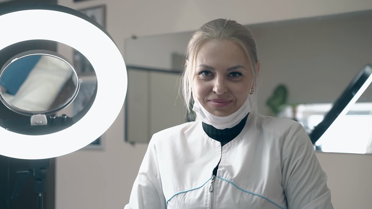 женщина-косметолог снимает маску на светодиодной лампе в салоне