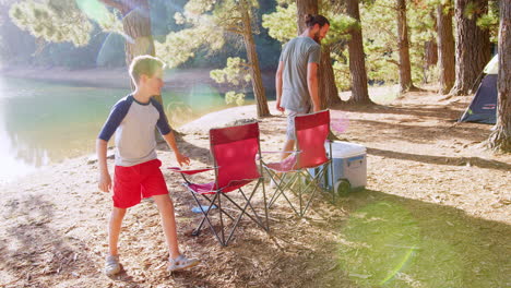 family with friends camp by lake on hiking adventure in forest