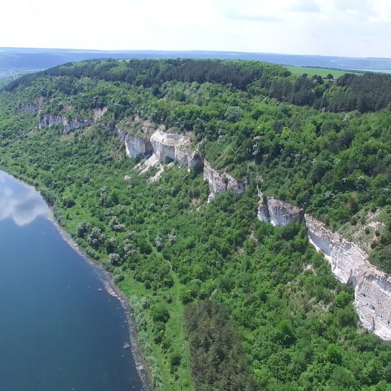 Wonderful landscape of rocks with a forest at the top and at the foot not far from river in the summer. Aerial view. Camera motion to forward.