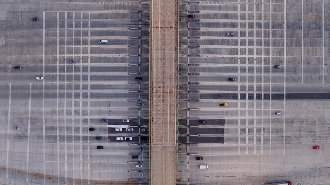 Ripresa aerea dall'alto di corsie di caselli autostradali con veicoli che si muovono attraverso un sistema stradale a griglia strutturata, drone