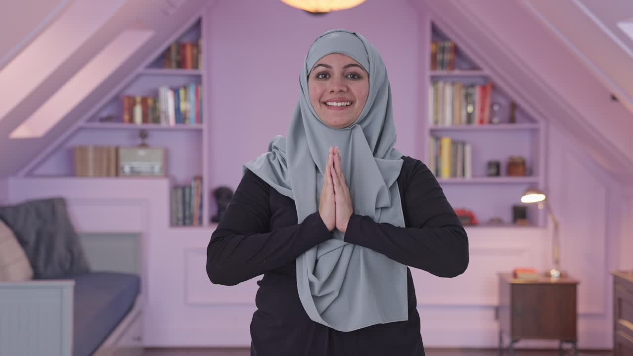 행복한 무슬림 여성이 나마스테를 하고 있습니다.