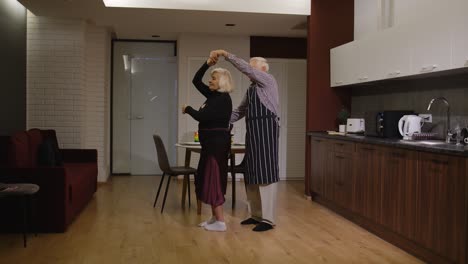 Senior-couple-in-love-have-romantic-evening,-dancing-together-in-kitchen,-celebrating-anniversary