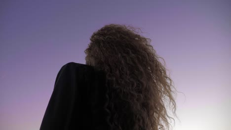 hermosa dama parada afuera bajo el cielo púrpura anhelando viajar - toma de primer plano