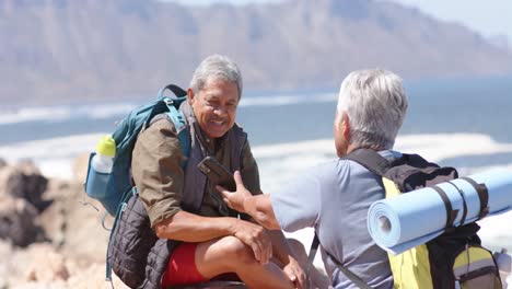 happy senior biracial couple in mountains taking photos with smartphone, in slow motion