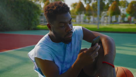 man using smartphone on a basketball court