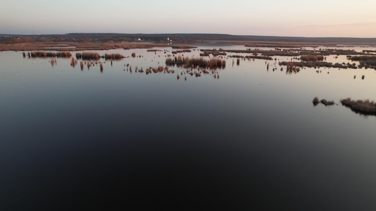 una serena vista aérea de un tranquilo paisaje del delta durante la puesta del sol con aguas tranquilas y tierra distante