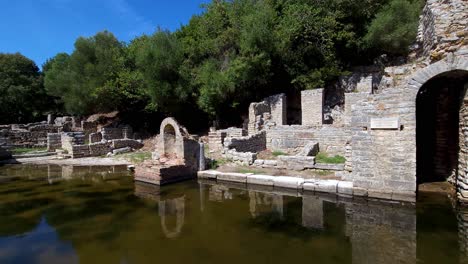 arched stone walls in the ancient city, mirrored in calm water ponds at butrint's archaeological site, discover the serenity