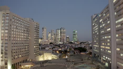 Volar-Entre-Edificios-En-La-Ciudad-De-Tel-aviv,-Noche,-Disparo-De-Drones,-Vista-De-La-Ciudad