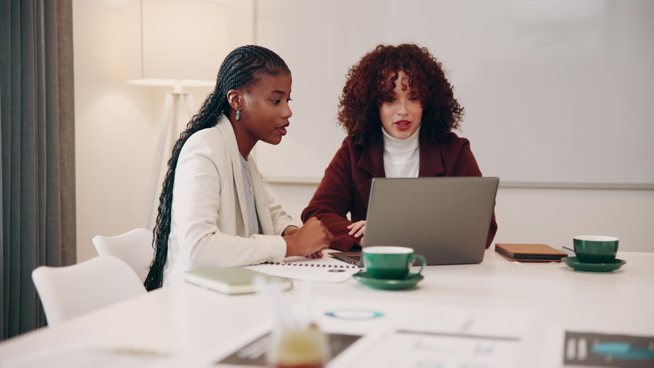 Due donne d'affari che collaborano su un laptop in una sala riunioni.